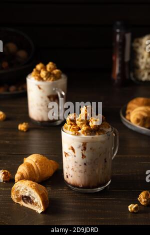 Mugs en verre avec milkshake au chocolat, pop-corn au caramel et chocolat croissants sur fond de bois Banque D'Images