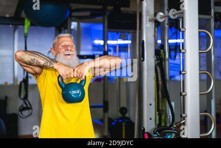 Homme de fitness senior faisant des exercices de cloche de bouilloire dans la salle de gym - Former des hommes matures dans le centre du club de bien-être Banque D'Images