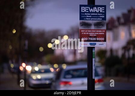 Deux yeux regardent une rue résidentielle de banlieue sombre, sur un panneau qui avertit les mordeurs de ne pas jeter de déchets dans cette rue du sud de Londres, le 4 novembre 2020, à Londres, en Angleterre. Banque D'Images