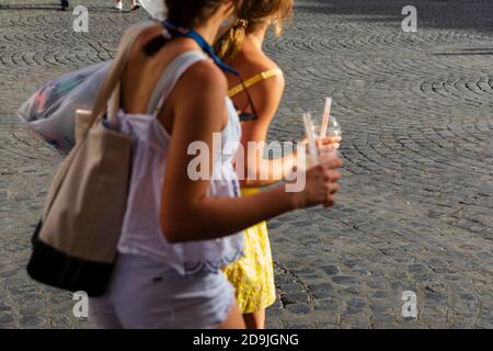 Deux adolescentes portant des tasses en plastique avec pailles sur la Piazza Santa Maria, Trastevere, Rome, Italie. Banque D'Images