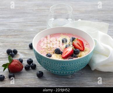 Un petit déjeuner sain et détox. Bol à smoothie avec sarrasin vert germé, fraises, bleuets et bananes sur une table en bois, mise au point sélective Banque D'Images