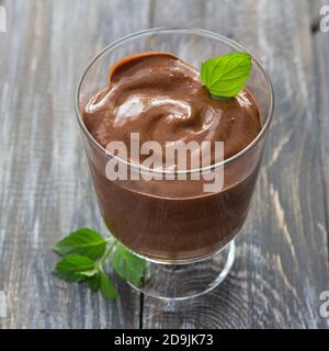Délicieuse mousse au chocolat végétalien avec banane, cacao et menthe en verre sur une surface en bois, mise au point sélective Banque D'Images