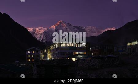 Gokyo, Népal - 11/20/2019: Belle vue des pavillons illuminés dans le petit village de Sherpa Gokyo (4,800m) dans la lumière du soir avec ciel violet. Banque D'Images