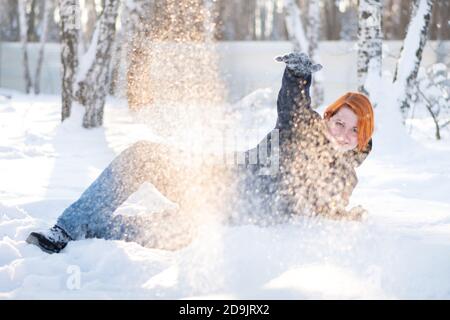 Jolie fille invite à jouer boules de neige se trouve sur la neige dans la forêt. Liberté et concept joyeux. Femme entourée de flocons de neige. Banque D'Images