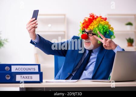 Homme d'affaires âgé clown travaillant dans le bureau Banque D'Images