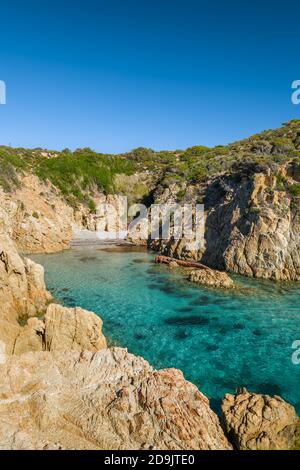 Une petite plage de sable et turquoise méditerranéen dans un endroit isolé crique rocheuse sous un ciel bleu profond près d'Ostriconi in La Balagne de Corse Banque D'Images