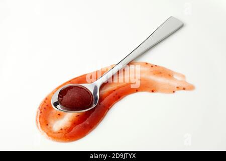 Sauce à base de marmelade rouge piquant dans une cuillère argentée une surface de courbure du pansement sur blanc avec un espace de copie pour les concepts publicitaires Banque D'Images