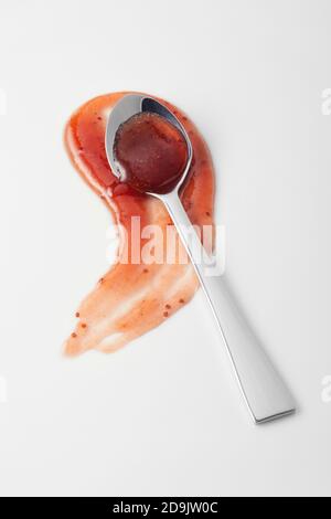 Délicieuse sauce marmelade rouge épicée sur blanc dans un cuillère argentée sur un blob courbé pour la publicité Banque D'Images