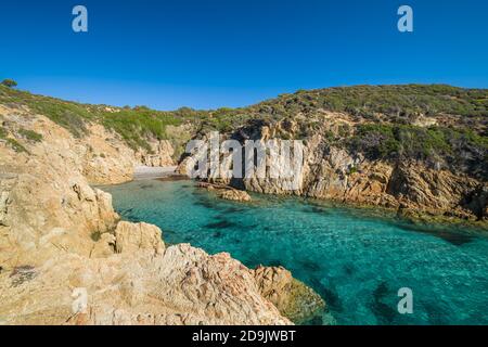 Une petite plage de sable et turquoise méditerranéen dans un endroit isolé crique rocheuse sous un ciel bleu profond près d'Ostriconi in La Balagne de Corse Banque D'Images