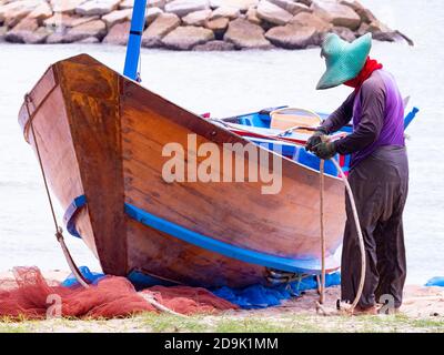 Pêcheur travaillant sur son bateau traditionnel en bois après une journée de pluie en mer dans la province de Rayong en Thaïlande. Banque D'Images