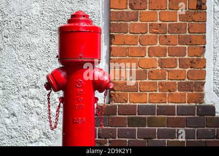 ancienne borne d'incendie rouge contre le mur de briques Banque D'Images