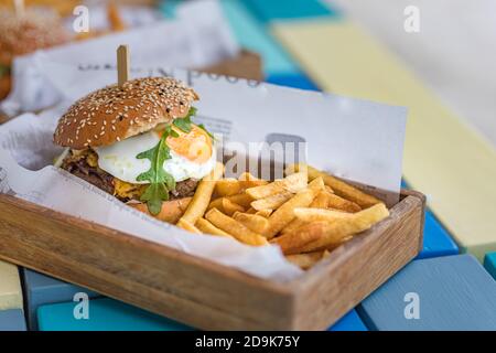 Hamburger et frites. Hamburger géant aux frites dans une assiette en bois. Hamburger gastronomique fait maison sur le plateau de table du restaurant extérieur Banque D'Images