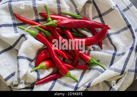 Piments rouges sur une serviette bleue et blanche. Légumes frais vue du dessus photo. Gros plan sur la texture du poivre de Cayenne. Banque D'Images