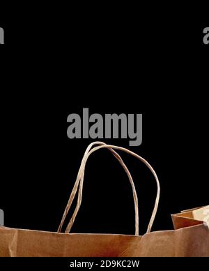 Sac de transport de papier marron vierge avec poignées pour le shopping. Sac en papier sur fond noir, attitude responsable envers l'environnement. Environnement Banque D'Images