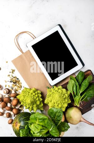 Tablette et sac de papier avec légumes et légumes verts. Vue de dessus Banque D'Images