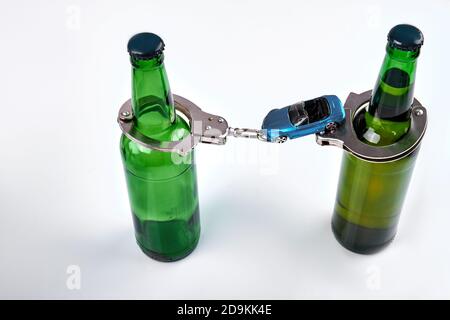 Composition de bouteilles de bière avec menottes et voiture. Banque D'Images
