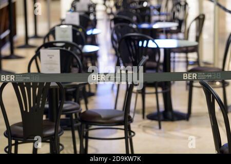 06 novembre 2020, Berlin, Schönefeld: Un ruban barrière avec le logo BER, mis en place pour se conformer aux règles de Corona, empêche les voyageurs de s'asseoir aux tables d'un café dans la zone hors taxes du terminal 1. Lors d'une visite de presse des commerces et des services de restauration, le patron de l'aéroport, Lütke-Daldrup, a présenté les boutiques. Photo: Soeren Stache/dpa-Zentralbild/dpa Banque D'Images