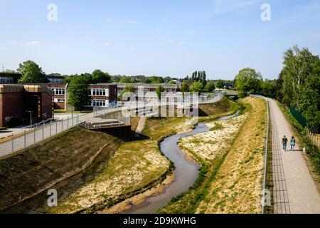 L'eau courante renatrée, le Hellbach appartient au système de l'Emscher, était auparavant un canal ouvert, au-dessus du sol des eaux usées, à gauche le Käthe-Kollwitz-Gesamtschule et la salle de classe bleue, à droite un nouveau sentier et sentier cyclable, conversion d'Emscher, Recklinghausen, région de Ruhr, Rhénanie-du-Nord-Westphalie, Allemagne Banque D'Images