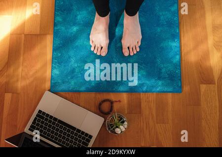 Gros plan des pieds féminins sur un tapis de yoga pendant un cours en ligne à la maison Banque D'Images