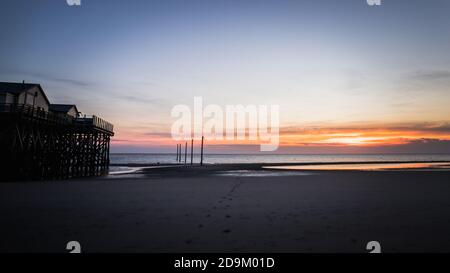 Coucher de soleil coloré sur la mer du Nord - dans le contre-jour du soleil une maison typique de pilotis, des logements de pile, des logements de pile qui défient les marées. Banque D'Images