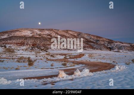 Chemin de ranch venteux dans la vallée de la montagne du Colorado, le soir de l'automne après le coucher du soleil, Red Mountain Open Space avec la lune de neige fraîche qui s'élève Banque D'Images