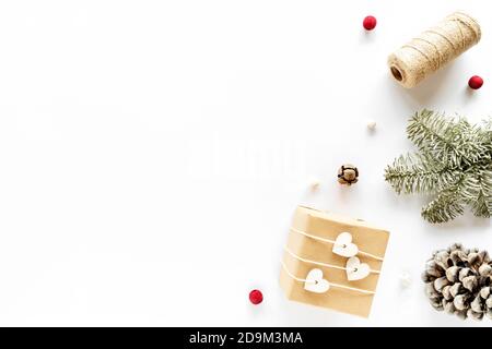 Boîte cadeau faite à la main, décorations de vacances, branches de sapin, cône de pin. Composition de Noël sur surface blanche. Noël bricolage cadeau concept. Plat, dessus Banque D'Images