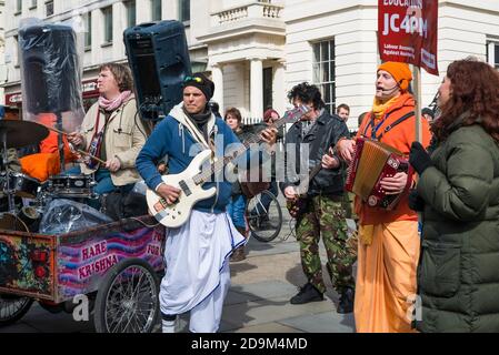 Un groupe de musiciens Hare Krishna divertit des gens à Charing Cross Road lors d'une marche de protestation dans le centre de Londres, en Angleterre, au Royaume-Uni. Banque D'Images