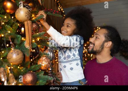 Gros plan père afro-américain avec fille décorant l'arbre de Noël Banque D'Images