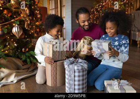 Gros plan la famille afro-américaine surjoyeuse déballant des cadeaux de Noël Banque D'Images