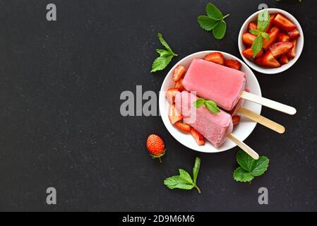 Glace à la fraise sur plaque blanche sur fond clair avec espace de copie. Tranches de fraises fraîches dans un bol. Vue de dessus, plan d'appartement. Banque D'Images