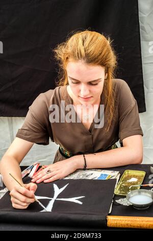 Sibiu City, Roumanie - 24 août 2019. Une fille vêtue de vêtements médiévaux peint la croix maltaise sur une toile noire au Festival médiéval traditionnel anuel Banque D'Images