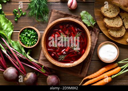 Soupe russe traditionnelle ukrainienne (borscht). Soupe de betteraves dans un bol sur fond de bois. Légumes frais sur la table. Vue de dessus, plan d'appartement Banque D'Images