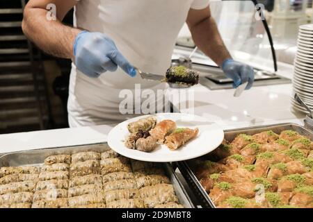 Personnel en gants servant des baklava turcs pour les touristes dans un hôtel tout compris en Turquie. Délicieux bonbons traditionnels sur une assiette. Assortiment de baklawa Banque D'Images