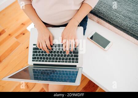 Femmes dactylographiant sur ordinateur portable, smartphone à proximité, vue de dessus Banque D'Images