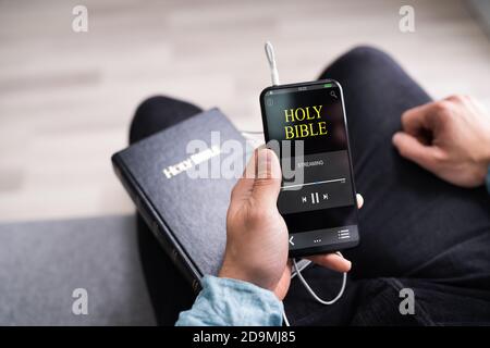 Christian Man lisant le livre de la Bible au téléphone et en priant Banque D'Images