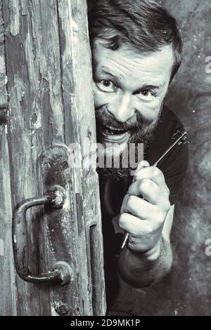 Homme barbu plein de joie avec la clé qui se déporte de la porte portrait de studio émotionnel Banque D'Images
