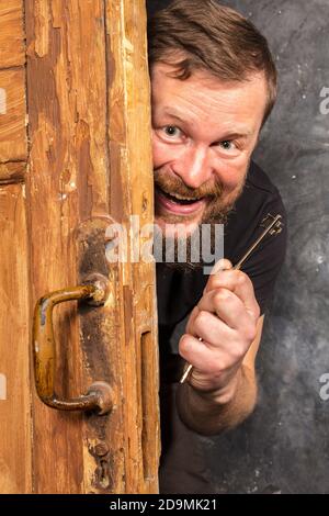 Homme barbu plein de joie avec la clé qui se déporte de la porte portrait de studio émotionnel Banque D'Images