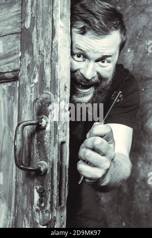 Homme barbu plein de joie avec la clé qui se déporte de la porte portrait de studio émotionnel Banque D'Images