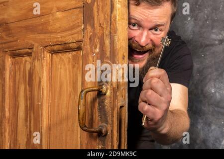 Homme barbu plein de joie avec la clé qui se déporte de la porte portrait de studio émotionnel Banque D'Images