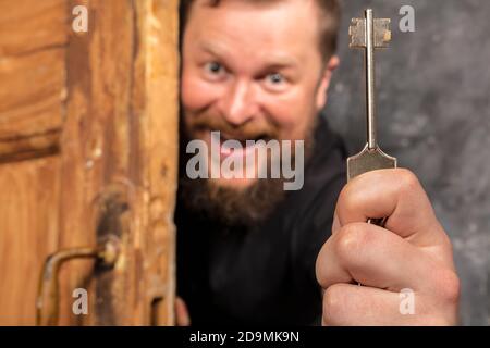 Homme barbu plein de joie avec la clé qui se déporte de la porte portrait de studio émotionnel Banque D'Images