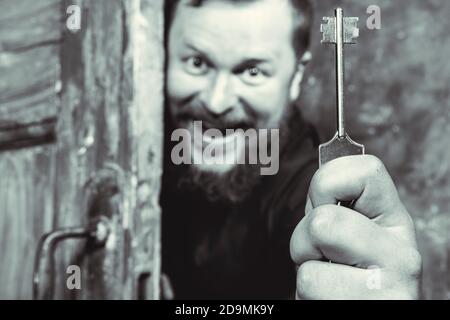 Homme barbu plein de joie avec la clé qui se déporte de la porte portrait de studio émotionnel Banque D'Images