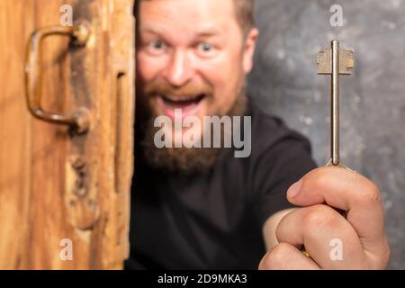 Homme barbu plein de joie avec la clé qui se déporte de la porte portrait de studio émotionnel Banque D'Images