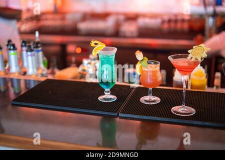 Cocktails colorés sur le comptoir du bar. Cocktails tropicaux sur la table du restaurant, prêts à servir. Fête nocturne, ambiance bar, bouteilles floues Banque D'Images
