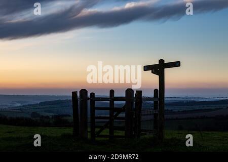 Une porte silhouettée et un panneau le long de South Downs Way, sur Ditchling Beacon dans Sussex Banque D'Images