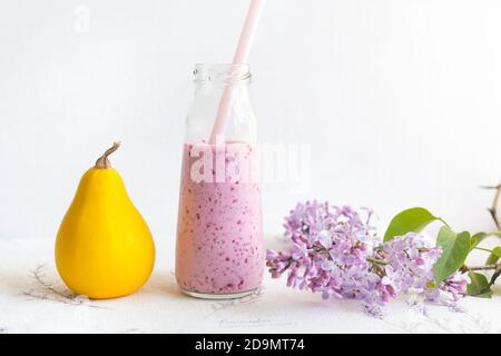 Smoothie aux baies dans un pot en verre avec une paille pour des cocktails, courgettes yellou, une branche de lilas, sur fond clair. Un mode de vie sain, une alimentation, un détox. R Banque D'Images