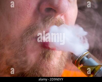 Gros plan de la bouche avec la moustache à l'aide de la cigarette électronique et de l'expiration jet de vapeur Banque D'Images