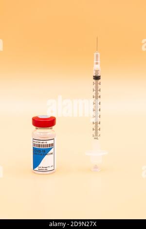 Un flacon du vaccin COVID-19 avec une seringue placé à la verticale à côté sur un fond orange. Concept de coronavirus Banque D'Images