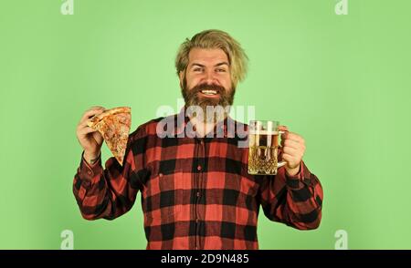 Il y a un verre de bière et de pizza. On regarde le football à la télévision. On y mange vite. Un homme qui a du bon barbu avec de la bière et de la pizza. on y mange de la cuisine italienne. l'italie est là. guy au bar boit de la bière et mange de la pizza. Banque D'Images