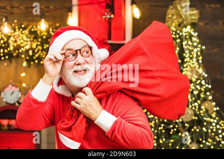 Joyeux Père Noël habillé de vêtements d'hiver pensez à Noël près de l'arbre de Noël. Banque D'Images