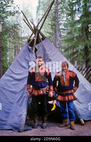 ANNÉES 1980 DEUX HOMMES FINLANDAIS EN AUTHENTIQUE VÊTEMENTS SÂMES REGARDANT CAMÉRA DEVANT UNE TENTE D'ABRI TRADITIONNELLE CERCLE ARCTIQUE FINLANDE - 087261 MAY001 HARS TRADITION DE FIERTÉ DE RENNE ELÉGANT AUTHENTIQUE OFFENSIVE COOPÉRATION ARCTIQUE SAMI JEUNE ADULTE HOMME CAUCASIEN ETHNICITÉ FINLANDE AUTOCHTONE LALANVERS LAPPS NORVÈGE PARTIES À L'ANCIENNE SAAMI SUÈDE SCANDINAVE Banque D'Images